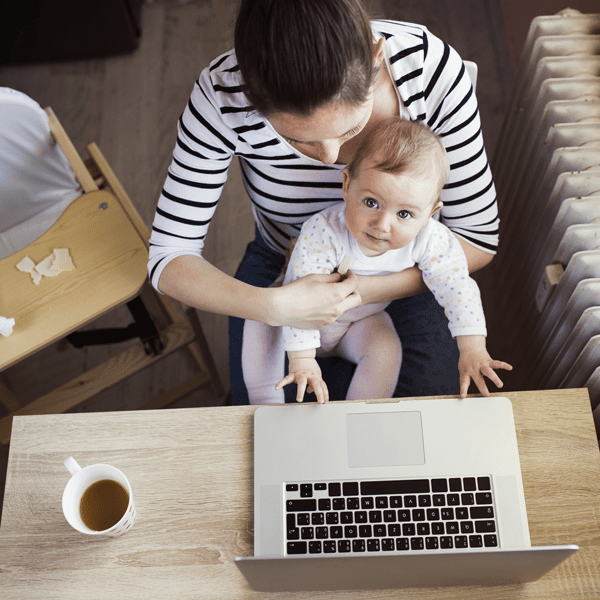 Mother working at computer with baby in arms