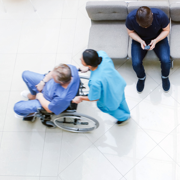 hospital worder pushing patient in wheelchair