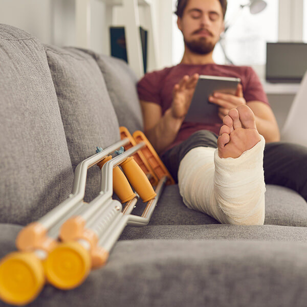 Man sitting on couch with a cast and crutches