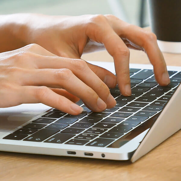 Hands typing homepage content using a laptop keyboard