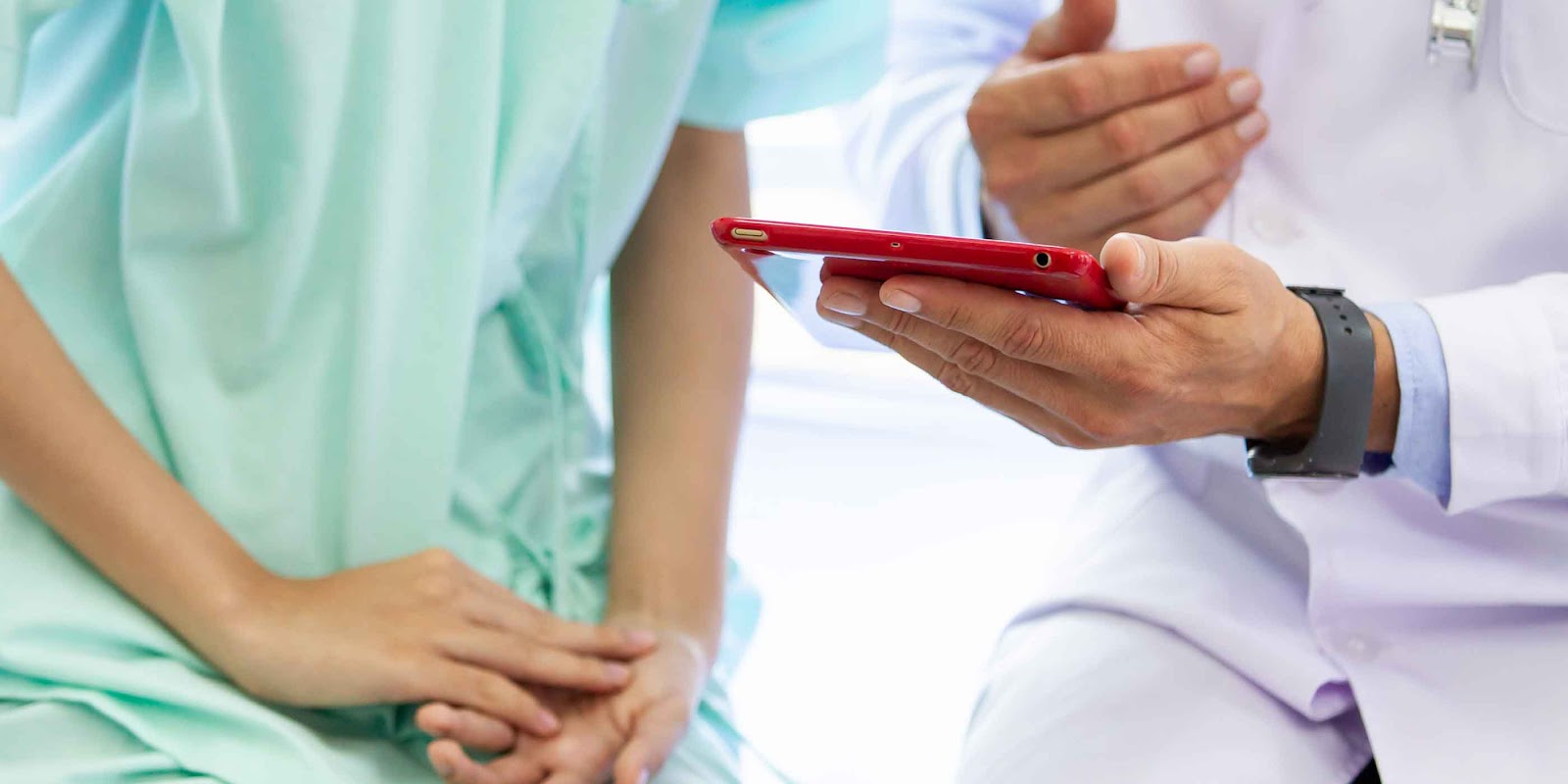 patient and physician looking at mobile device together